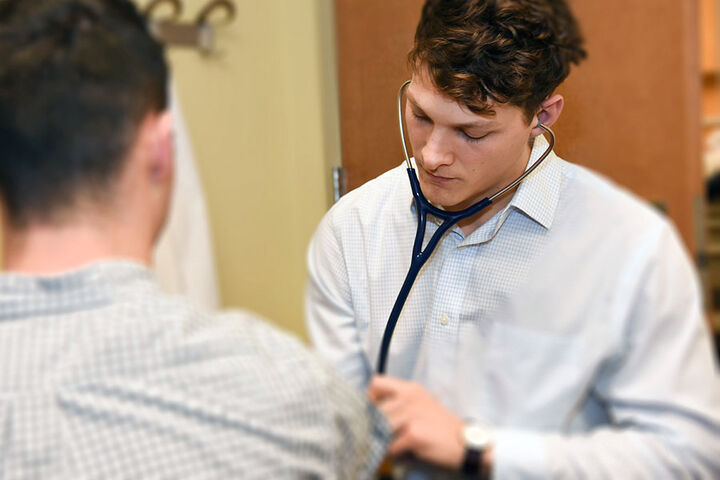A medical student performs an exam with a stethoscope.